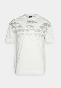 T-shirt bianco a maniche corte con piccoli testi neri sparsi che formano un motivo geometrico sulla parte superiore del petto e sulle spalle.