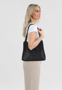 Borsa a tote in pelle nera con un design rotondo in rilievo, dotata di due manici robusti e una superficie liscia. Forma semplice e versatile.