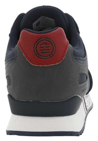 Donkerblauwe en grijze sneaker met een rode hieltab, gestructureerde bovenkant, logo-detail en een witte gemarmerde zool met zwarte accenten.