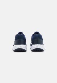 Zapatillas deportivas azul marino con parte superior de malla texturizada, suela blanca y banda de rodadura negra. Presentan un collar almohadillado y un diseño minimalista.