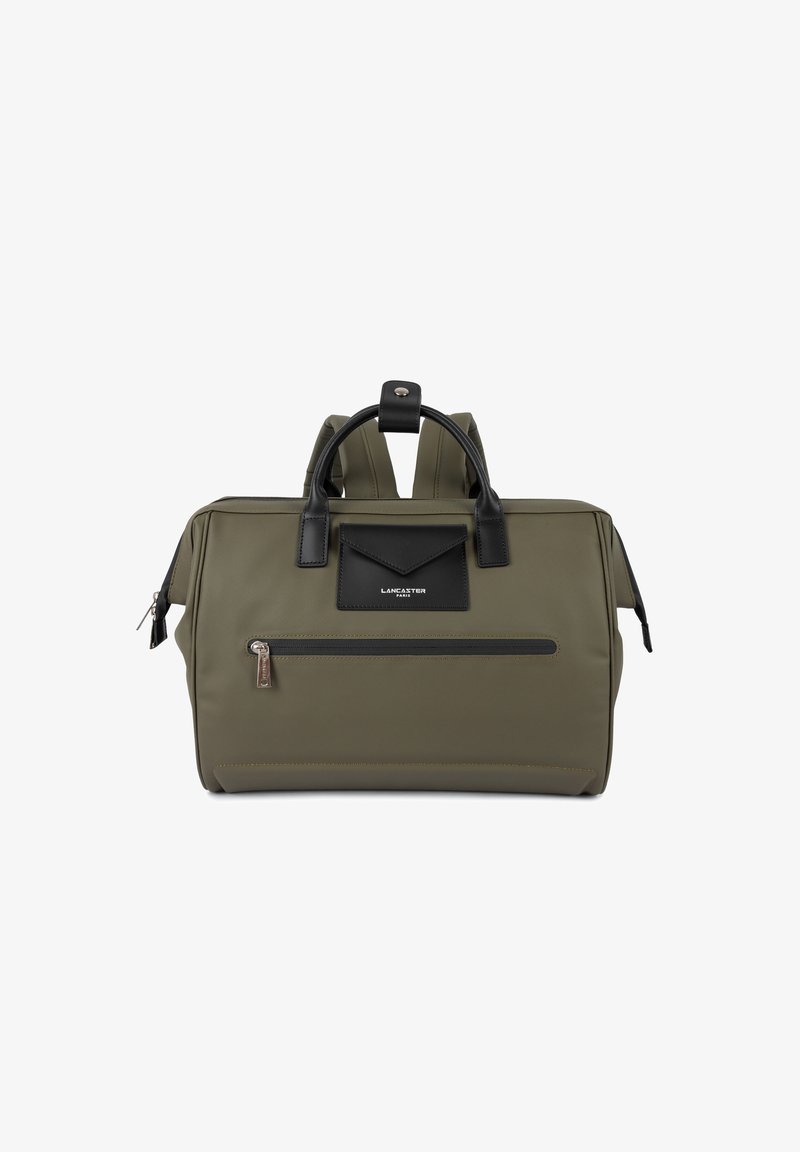 Zaino rettangolare verde oliva con manici in pelle nera, tasca frontale con zip e logo "Lancaster Paris" su un patch in pelle nera.