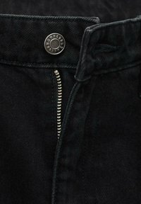 Black denim jeans featuring a metal button at the waistband and a silver zipper with teeth visible along the fly.