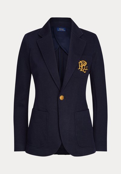 Veste bleu marine avec bouton doré, deux poches avant et logo brodé en or sur la poche poitrine gauche.