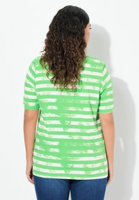 Camiseta de rayas verdes y blancas con un corte relajado y mangas cortas. La camiseta cuenta con una suave textura de algodón y un patrón ligeramente desvanecido.