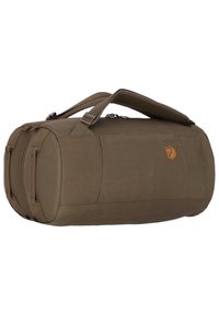 Ruskea duffel-laukku, joka on valmistettu kestävästä kankaasta, pyöreällä muotoilulla, kahdella kantohihnalla ja pienellä logolapulla sivussa.