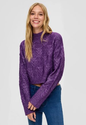 Lila verkürzter Pullover mit Zopfmuster, geripptem Ausschnitt und Bündchen, kombiniert mit blauen Jeans. Weiche Textur und lässige Passform.