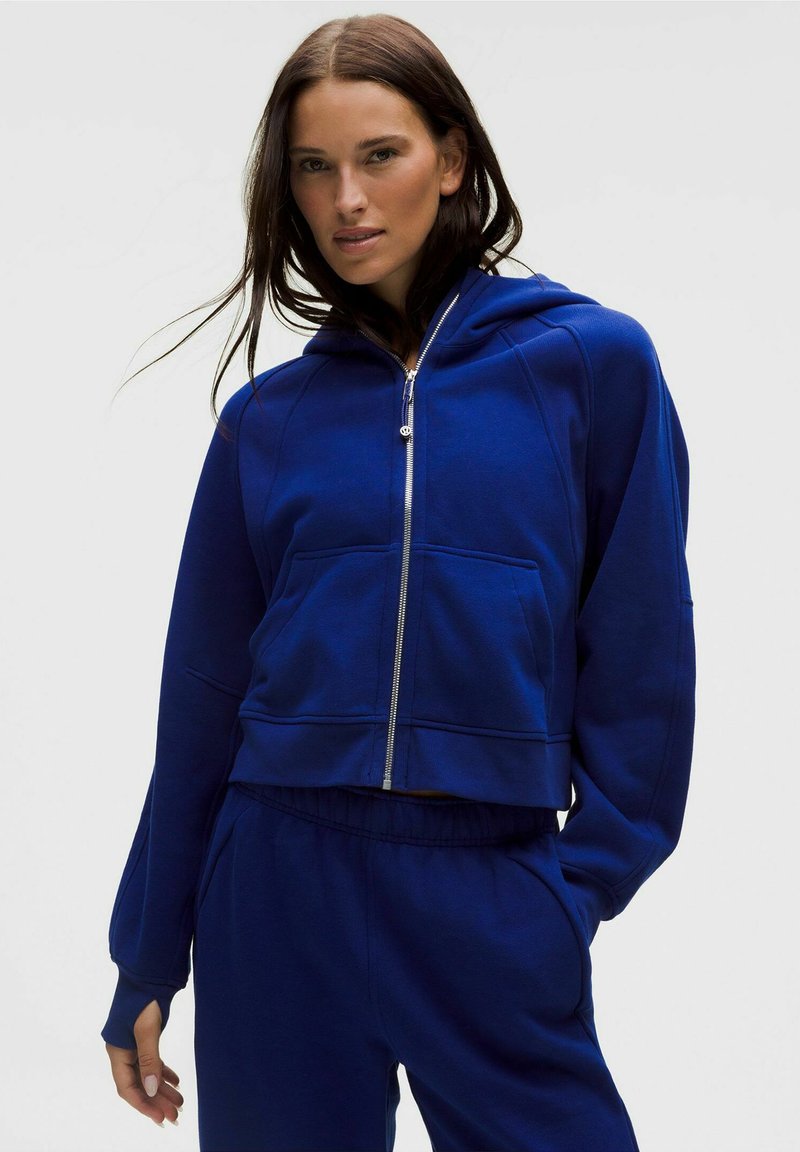 Felpa blu tagliata, realizzata in tessuto morbido, con zip frontale, grande tasca e vestibilità comoda con polsini a coste.