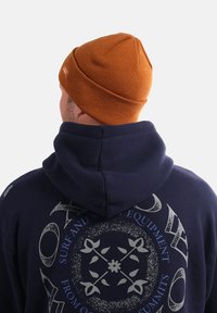 Sweat à capuche navy avec un grand motif gris au dos et un bonnet en tricot orange. Le sweat à capuche possède un col à cordon et une texture douce.