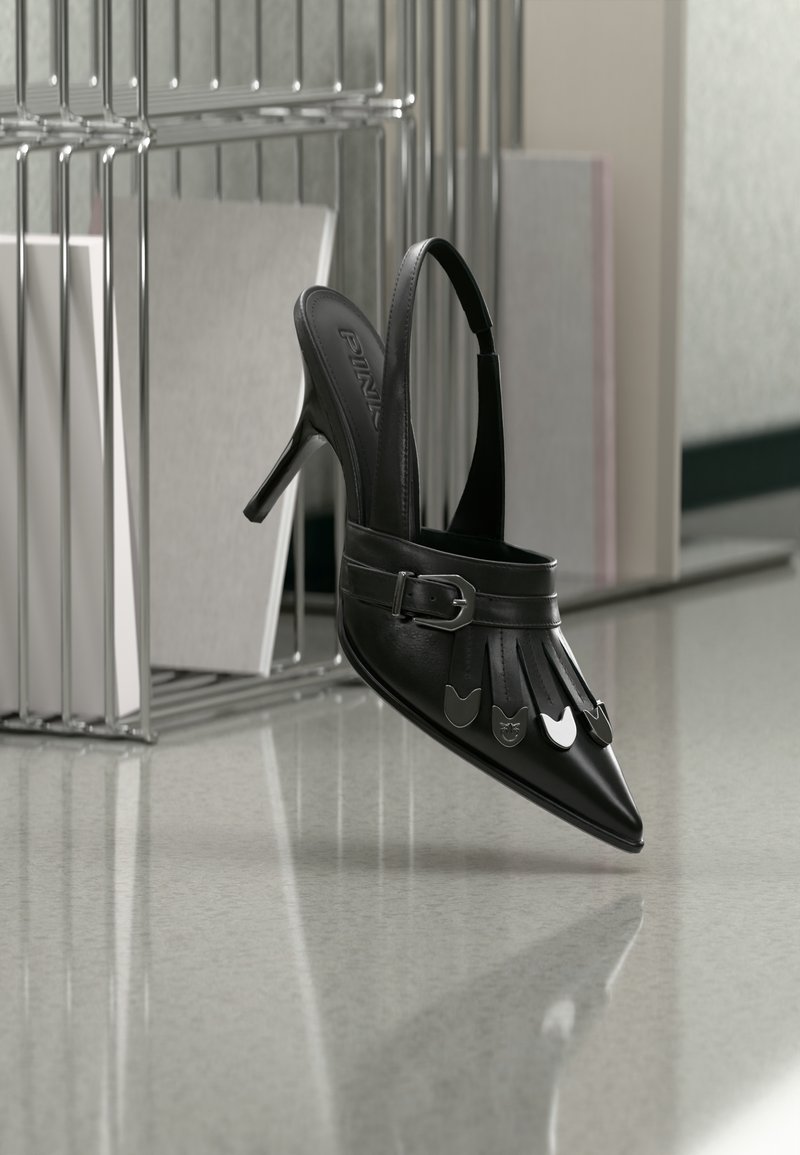 Escarpin slingback en cuir noir avec talon haut, bout pointu, ornements argentés en forme de chat et bride à boucle, présenté sur une surface réfléchissante.