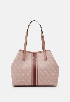 Różowa torba typu tote z podwójnymi uchwytami, wzór z jasnymi monogramami, centralne pionowe paski i metalowe logo GUESS z przodu.