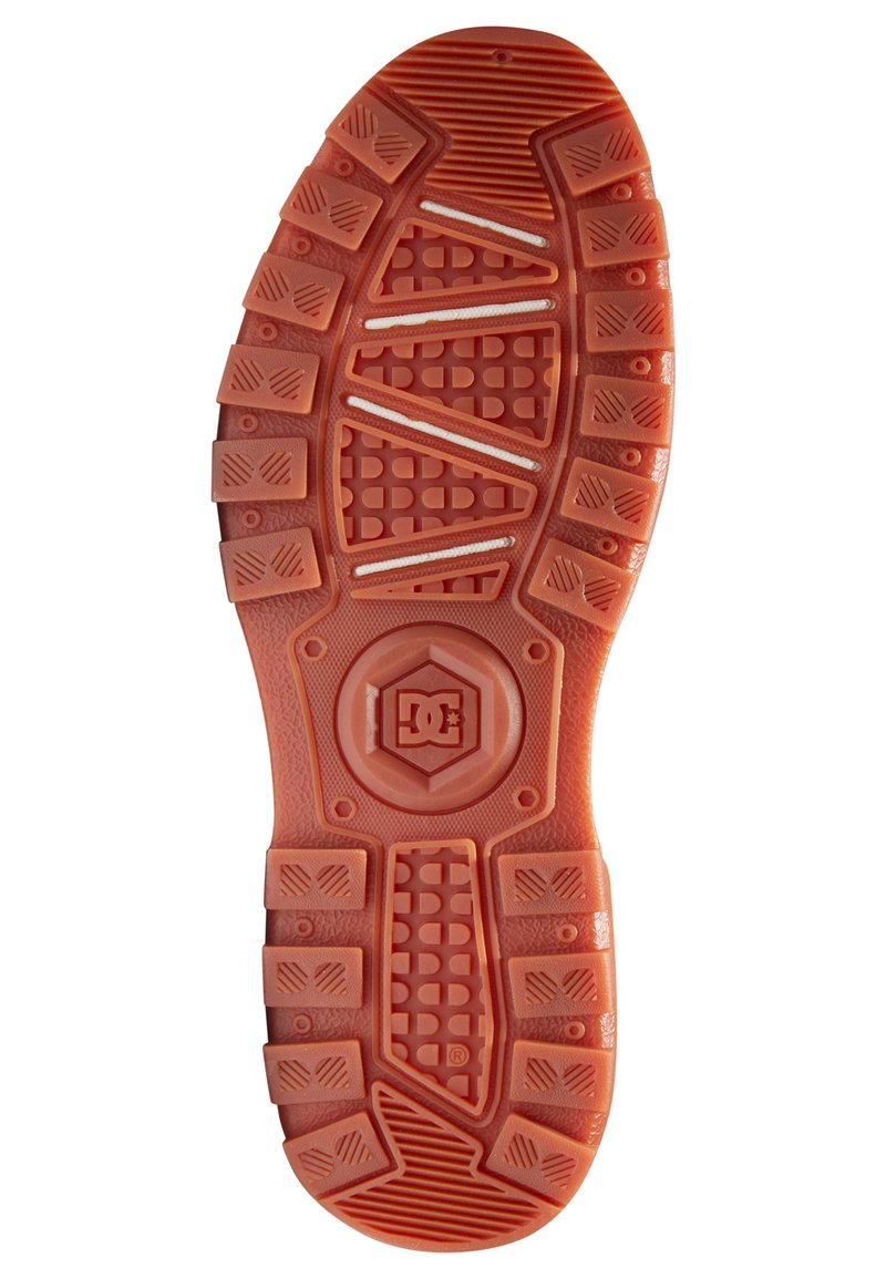 Orangene Gummischuhsohle mit einer strukturierten Oberfläche, die sechseckige Muster, tiefe Rillen und ein kreisförmiges Logo in der Mitte aufweist.