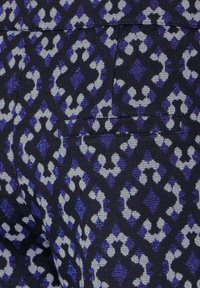 Kangas, jossa on geometrinen kaavio tummansinisillä, purppuranpunaista ja harmaita sävyillä. Kankaassa on hieman kimallusta ja teksturoitu pinta.