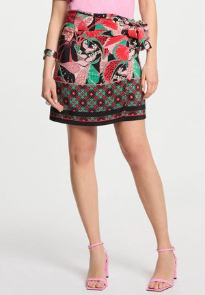 Falda corta con estampado floral en tonos vibrantes de rosa, rojo y verde; presenta una cintura atada con un ribete negro en el dobladillo.