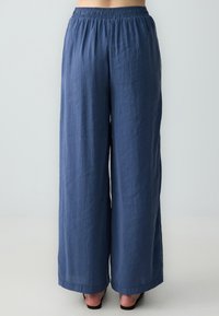 Pantaloni larghi blu realizzati in tessuto leggero con vita elastica, caratterizzati da una vestibilità comoda e una leggera trama, stile lungo fino al pavimento.