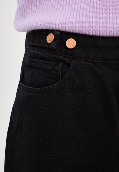 Jeans negri din denim cu croială ajustată, dotate cu nasturi de culoare cuprată și o mică buzunar frontal. Țesătură texturată cu un finisaj neted.