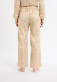 Spodnie od piżamy w żółtym kolorze o gładkiej fakturze, z zabawnym wzorem jelenia i elastycznym pasem dla wygody.