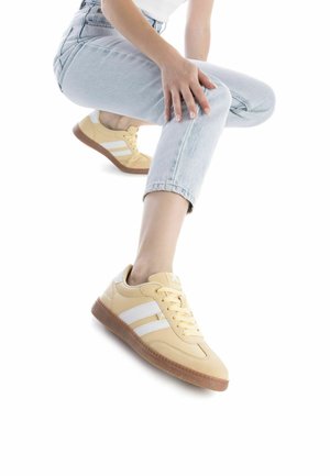 Zapatillas de color amarillo claro con rayas blancas y suela de goma beige. Parte superior de cuero suave, punta redondeada y diseño de cordones en la parte frontal.