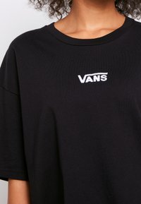 Czarna koszulka z bawełny z białym haftowanym logo "VANS" na piersi. Krótkie rękawy i okrągły dekolt. Miękka tekstura.