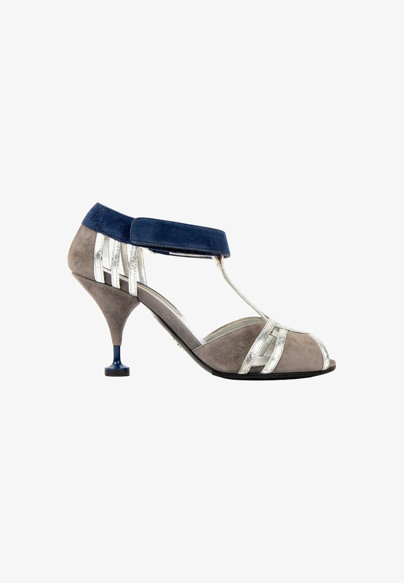 Chaussure à talons hauts pour femme en daim gris avec des lanières argentées, bride de cheville bleu marine et talon étroit bleu avec une base plus large.