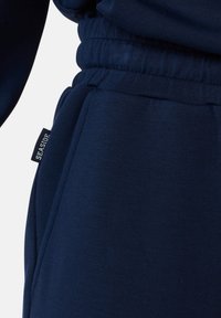 Marineblaues Sweatshirt mit lockerer Passform, das einen strukturierten Stoff und einen elastischen Bund hat. Enthält ein Etikett mit der Aufschrift "SEASIDE."