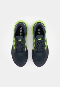 Baskets de sport bleu marine et vert fluo avec une tige texturée, des lacets plats et un logo à trois bandes, conçues pour la performance et le confort.
