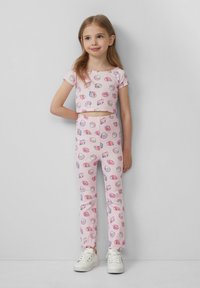 Zweiteiliges Outfit für Kinder mit einem kurzärmligen Cropped-Top und Leggings, beide in zartem Rosa mit Muschelmuster. Weicher Stoff, taillierte Form.