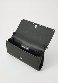 Svart lærpung med teksturert overflate, sølvfarget hardware, trykknapplukking og et interiørmerke. Åpner for å avsløre flere rom.