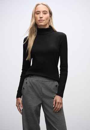 Sort langærmet turtleneck top med ribbet tekstur, sammen med grå plaid bukser med høj talje og knapdetaljer.