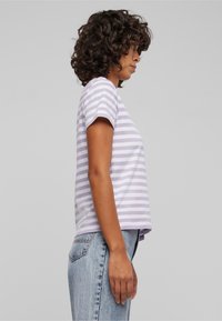Stripet T-skjorte i lavendel og hvitt, kortermet, avslappet passform, med rund hals. Kombinert med lyseblå, høy midje jeans.