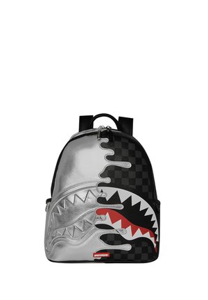 Zaino con design diviso: un lato argento metallizzato con denti di squalo in rilievo, l'altro lato a scacchiera nera con grafica della bocca di squalo rossa e bianca.