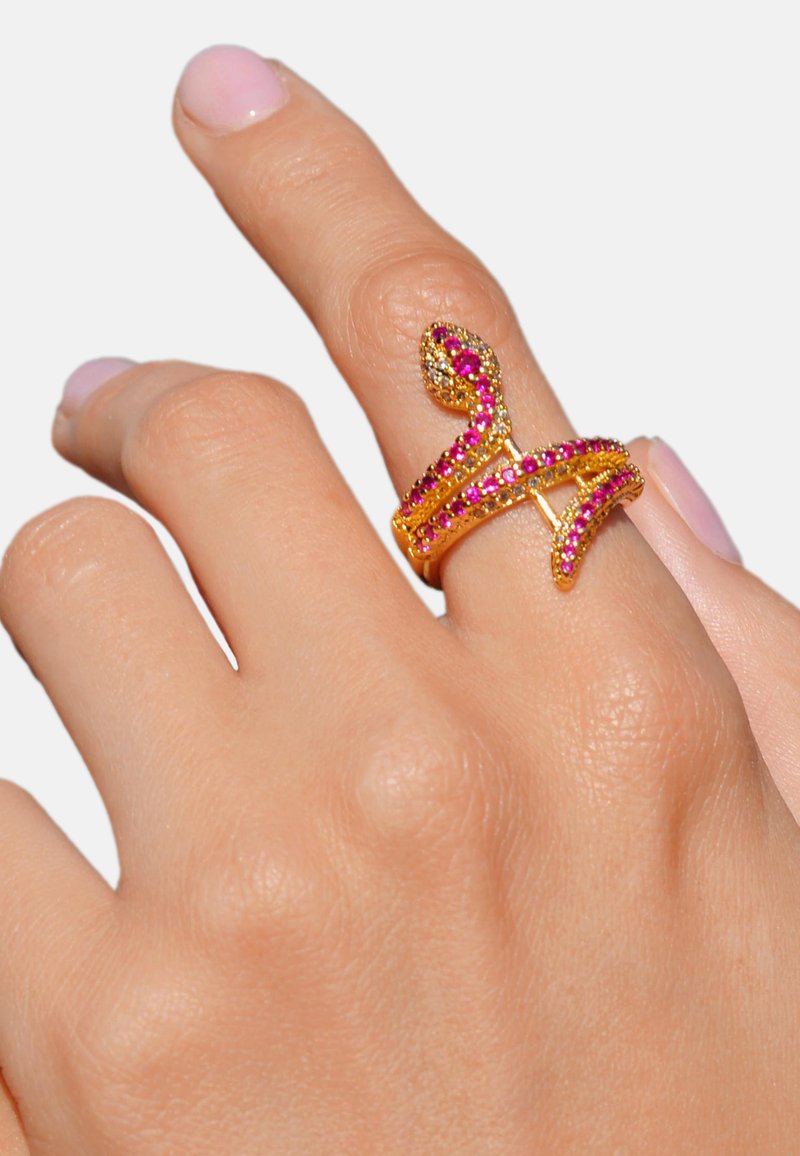 Bague en métal doré avec un design entrelacé, ornée de rhinestones roses et transparents, dotée d'un accent enroulé sur le dessus.