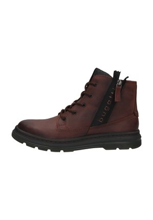 Braune Leder-Stiefelette mit schwarzen Akzenten, sechs Ösen-Schnürung, seitlichem Reißverschluss und strukturiertem Gummisohle. Runde Zehenform.