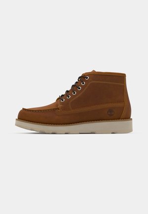Brown leather mid-cut boots with a round toe, black laces, and a textured surface. Features a light-colored sole and tree logo detail.