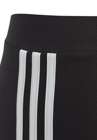 Leggings sportivi neri con una cintura larga presentano tre strisce bianche verticali lungo il lato. Il materiale sembra elastico e liscio.