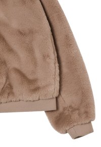 Giacca in finta pelliccia marrone con una consistenza morbida, polsini a coste e una silhouette rilassata. Il tessuto presenta una leggera lucentezza e una finitura morbida.