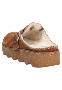 Brązowy zamszowy but wsuwany z miękką wewnętrzną wyściółką, masywną korkową podeszwą i ozdobną srebrną klamrą. Teksturowane przeszycia wzdłuż brzegów.