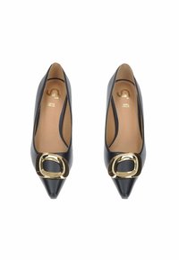 Un paio di ballerine in pelle nera con punta a stiletto e grandi dettagli in fibbia dorata su sfondo bianco.