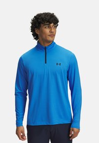 Blaues langärmliges Sportoberteil mit einem halben Reißverschlusskragen und schwarzem Logo. Hergestellt aus glattem, leichtem Material, mit eng anliegenden Ärmeln und geradem Saum.