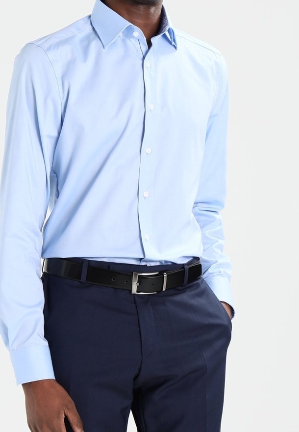 Lichtblauw overhemdd met een klassieke kraag, knoopsluiting aan de voorkant, lange mouwen, gecombineerd met donkerblauwe broek en een zwarte riem.