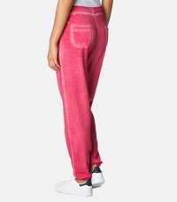 Roza bombažna trenirka s sproščenim krojem, ki vključuje en zadnji žep in kontrastne šive. V kombinaciji z belimi supergami za sproščen videz.