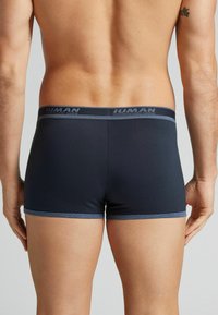 Mörkblå herrboxershorts i stretchigt tyg, med en kontrasterande midja med varumärke och en snug passform runt benen.