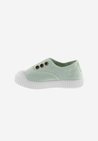 Scarpa slip-on in tela verde chiaro con suola e punta in gomma bianca, caratterizzata da tre fori in metallo sui lati, esposta su uno sfondo bianco.