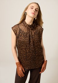 Top marrone trasparente con motivo a stampa leopardata, caratterizzato da un collo alto e maniche a cappuccio, abbinato a guanti di pelle marrone.