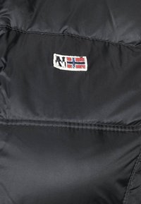 Schwarze, puffige Jacke aus Stoff mit horizontalen Nähten. Verfügt über ein kleines gesticktes Logo mit einer norwegischen Flagge, das rote, weiße und blaue Akzente zeigt.