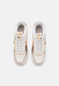 Sneakers in pelle bianca con dettagli in stampa leopardata, swoosh beige e punta perforata. Presentano lacci bianchi e linguetta con il marchio. Design pulito.