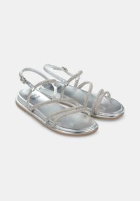 Zilveren platte sandalen met meerdere metalen banden, een verstelbare enkelgesp en een glanzende zilveren voetbed met een gestructureerde zool.