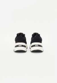 Black athletic sneakers with a mix of suede and mesh materials, featuring a white sole and a prominent "DIESEL" logo on the heel.