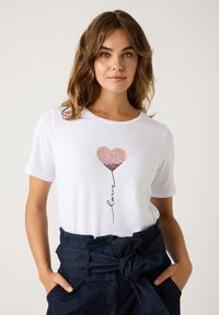 Weißes Baumwoll-T-Shirt mit einem glitzernden Herz-Graphic in Rosa- und Goldtönen, begleitet von dem Wort "Liebe" in einer geschwungenen Schriftart.