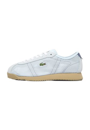 White mesh low-top sneaker with beige sole, white laces, and green crocodile logo on the side.