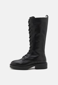 Bottes montantes à lacets noires en cuir lisse. Présentent un bout rond et une semelle plate et texturée, avec une languette à l'arrière.